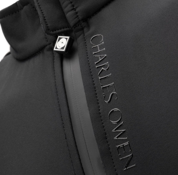 Close-up of a black puffer jacket featuring a vertical metallic zipper with the brand name CHARLES OWEN embossed on the side and a silver-tone logo tab near the collar.