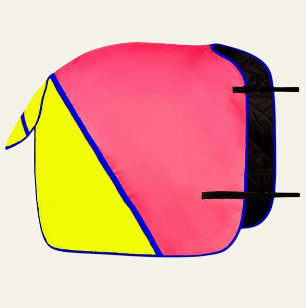 A colorful horse saddle pad with a bright pink and neon yellow geometric design, outlined in blue, featuring black straps on the side, set against a plain off-white background.
