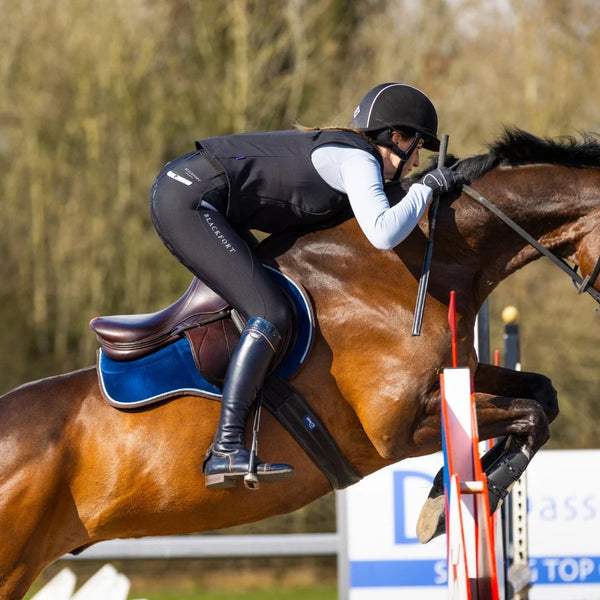 Equestrian rider on a horse jumping over an obstacle in an outdoor setting
