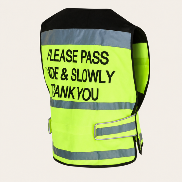 A high-visibility safety vest shown from the back, featuring a bright neon yellow-green body with reflective silver stripes and bold black text that reads 'PLEASE PASS SIDE & SLOWLY THANK YOU'.